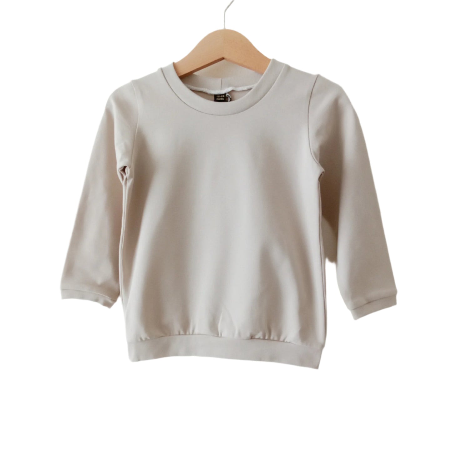 light beige long-sleeved plain baby t-shirt, displayed on a hanger
