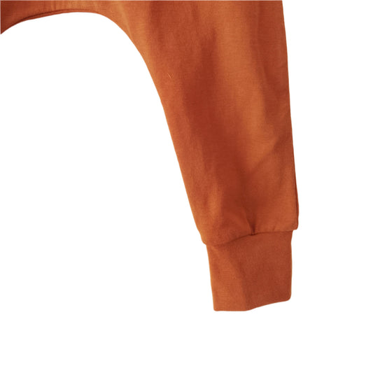 closeup of ankle detail of a pair of dark orange, plain jersey baby leggings