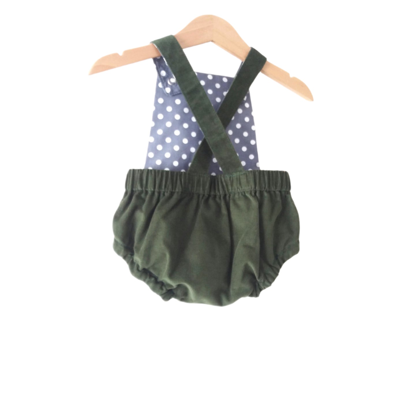 forest green corduroy bloomer-style baby romper with grey polka dot lining, displayed on a wooden hanger