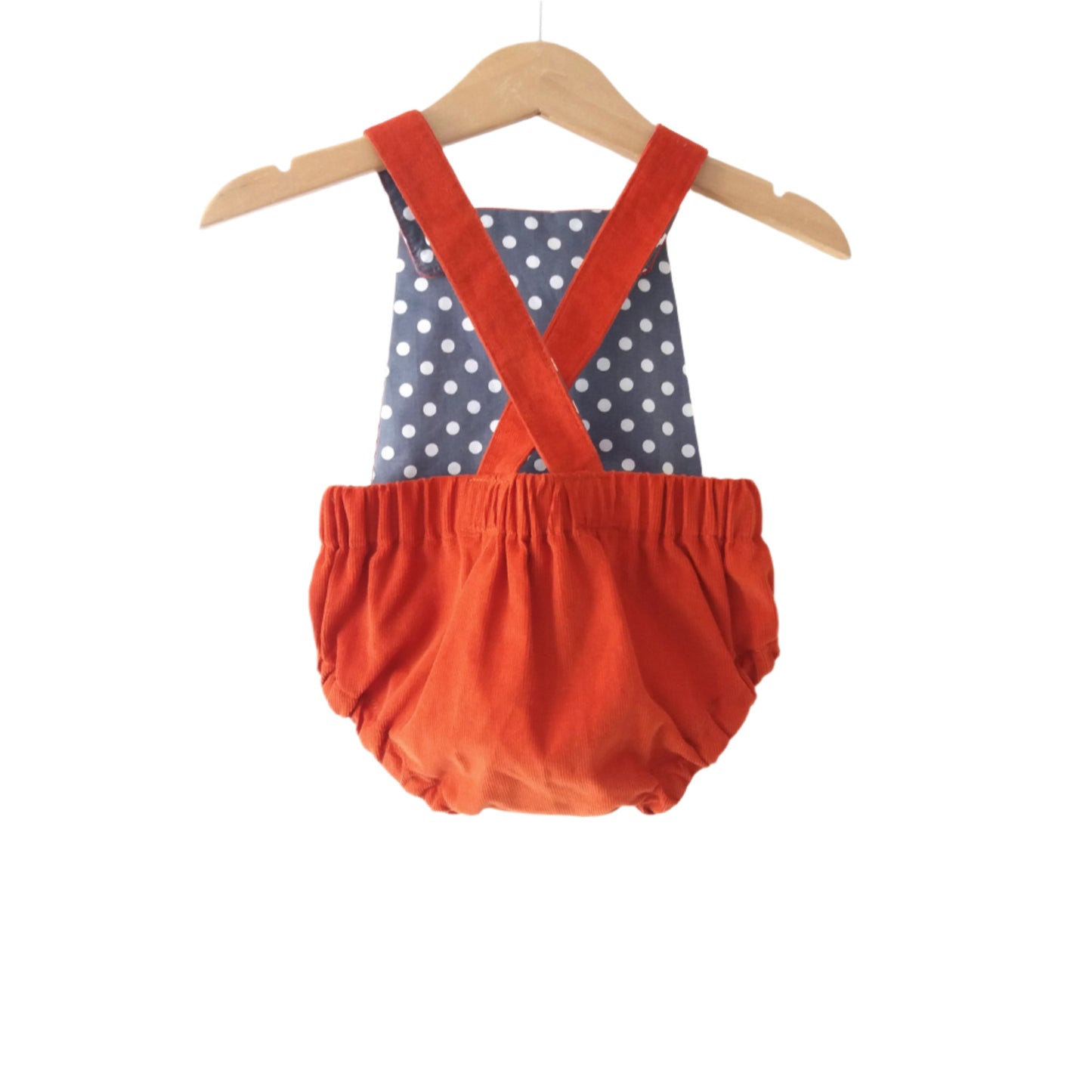 rust corduroy bloomer-style baby romper with grey polka dot lining, displayed on a hanger
