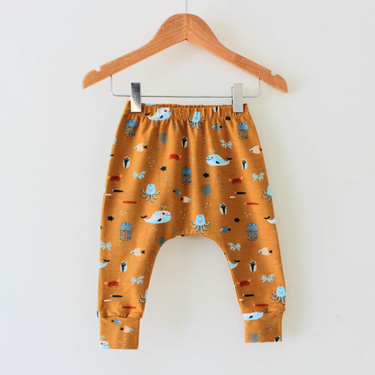 A pair of caramel-coloured baby leggings, featuring an all-over print of different sea creatures. 