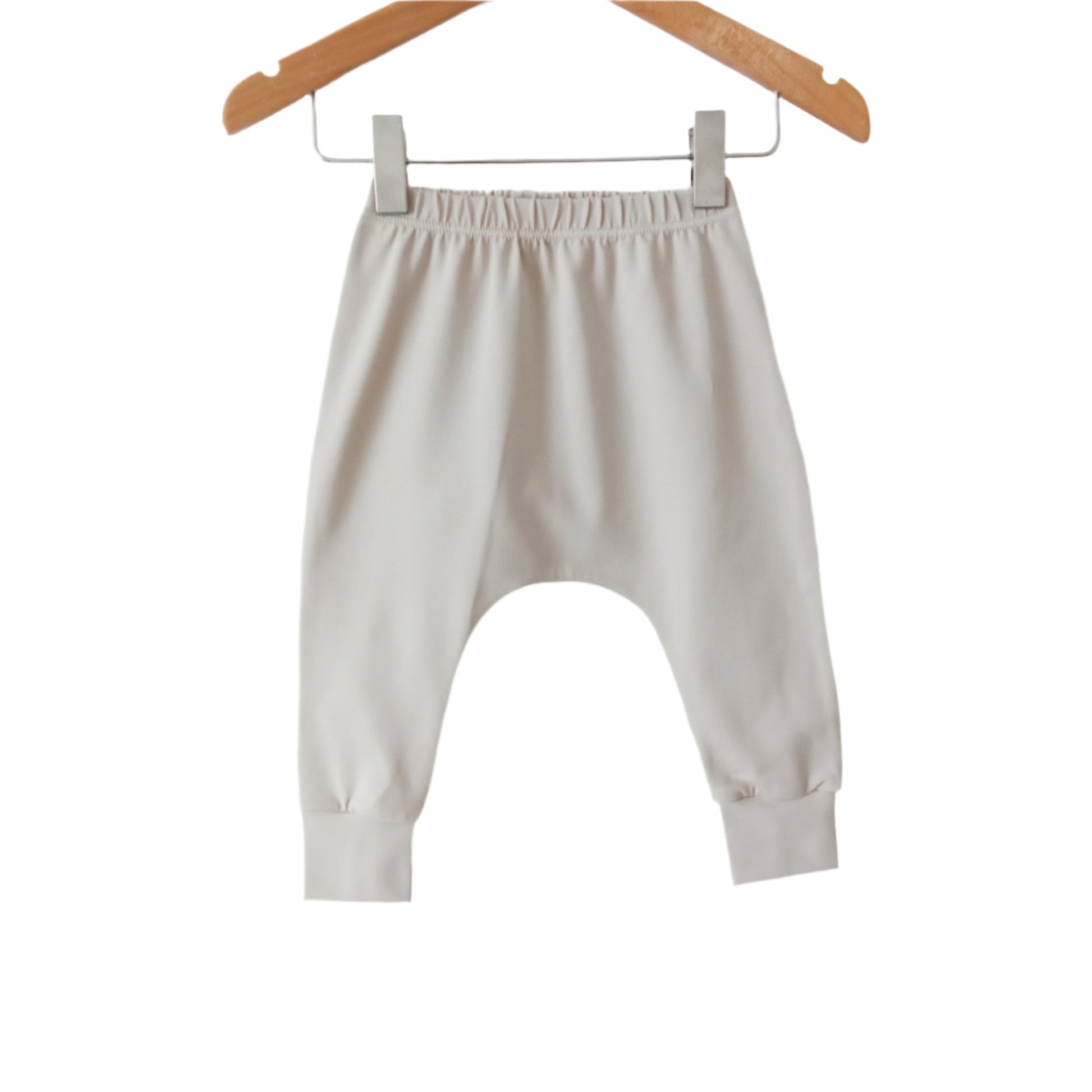 plain light beige coloured harem baby leggings, displayed on a hanger