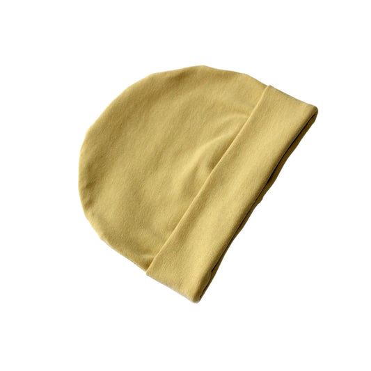 still life image of a plain jersey, light yellow beanie hat on a white background